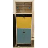 Cream, blue and yellow utility cabinet with glass sliding doors to top section, with single drawer,