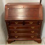 A reproduction mahogany bureau with fall front revealing internal pigeon holes and drawers,