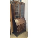 An oak bureau bookcase with two glazed doors above fall front bureau internally fitted with pigeon