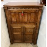 Dark oak carved drinks cabinet with fall front over a two door cupboard,