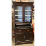 A dark stained pine wall unit with two glazed doors over two drawer two door base,