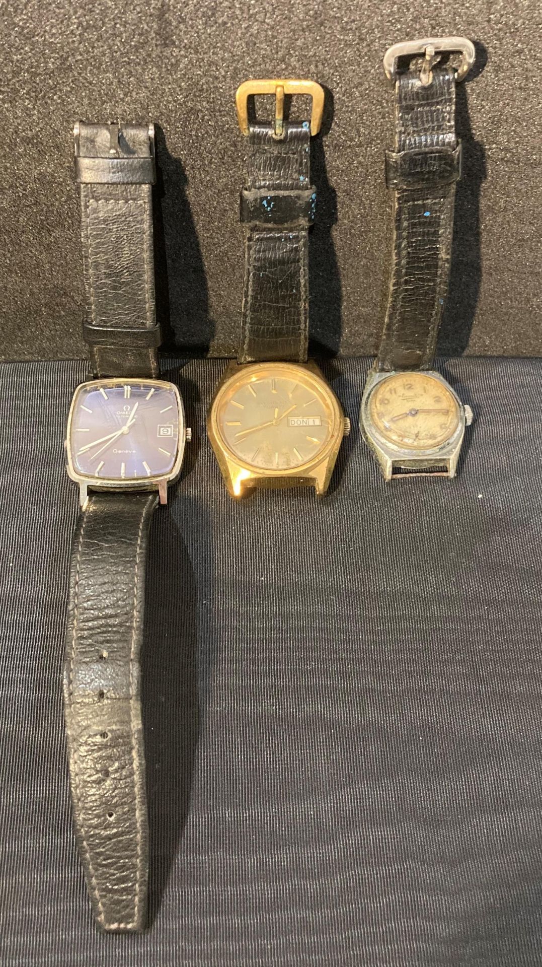 Three gents watches by Omega Automatic Geneve in working condition working with black leather trap