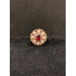 9ct gold [stamped: 375] ring with red central stone surrounded by eight seed pearls (size L).