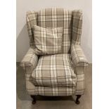 Wing-back armchair in a tartan latte coloured fabric on dark cabriole legs with matching cushion