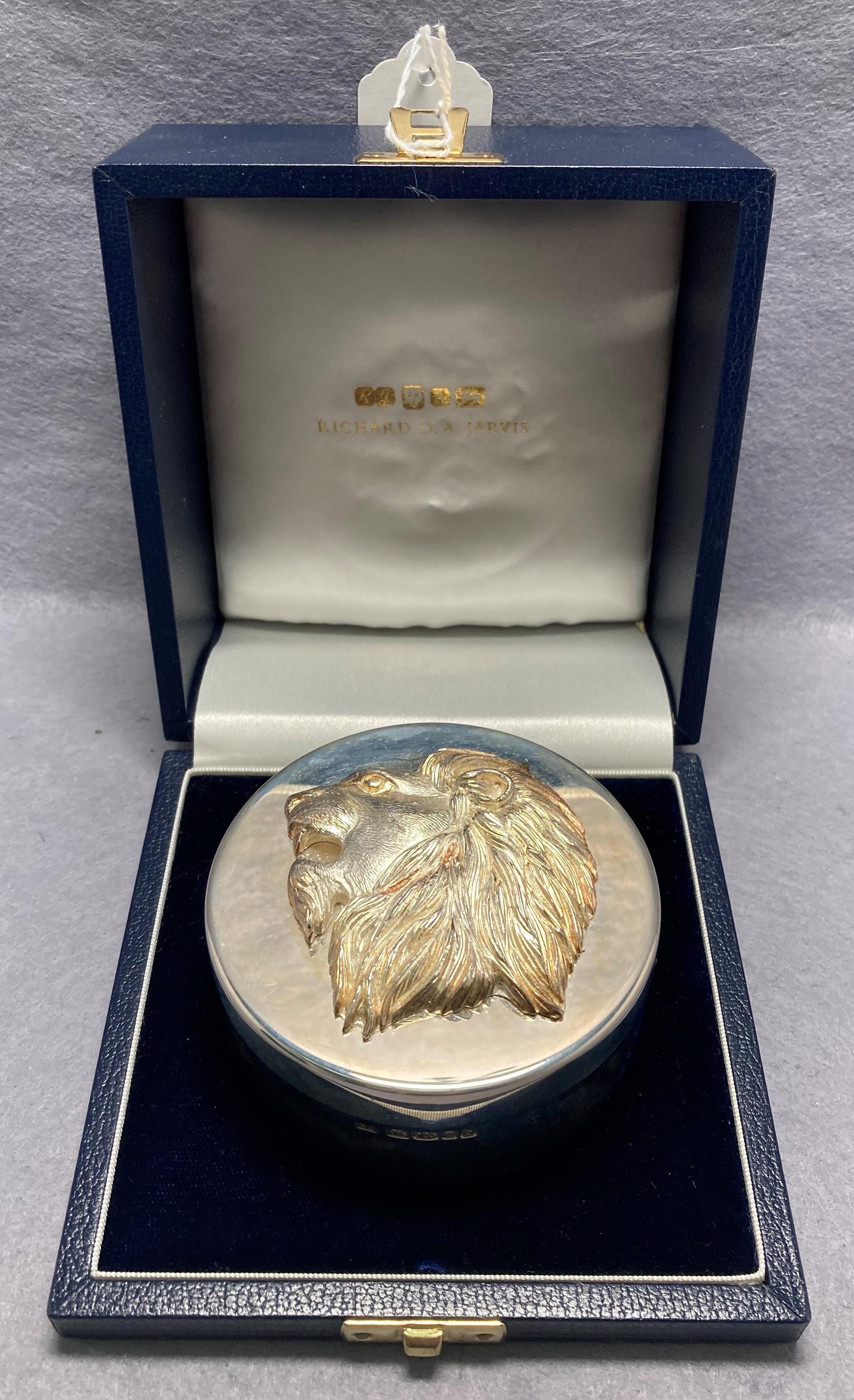 Silver [hallmarked] circular box with lions head lid in display case by RICHARD O A JARVIS.
