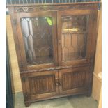 An oak four door bookcase with two leaded glass doors and two lower doors with scroll panels,