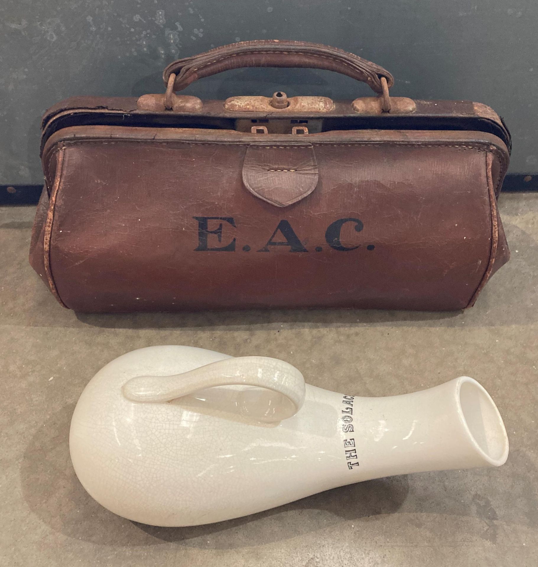 Brown leather doctors' bag with initials E A C and a ceramic 'The Solace Urine Bottle' (saleroom