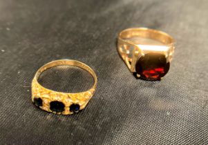 Two gold rings - one 9ct [stamped: 375 - size O] with a dark red stone in the centre and the other