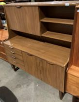 A teak veneered wall unit with drop down door and open shelves atop a four drawer two door base 125
