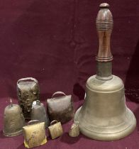 A large brass hand bell with a mahogany handle 33cm to top of handle and six smaller bells