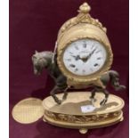 A brass and metal mantel clock with the clock mounted on a horse,