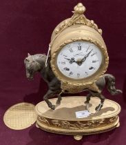 A brass and metal mantel clock with the clock mounted on a horse,
