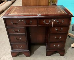 A mahogany finish eight-drawer twin pedestal kneehole desk with dark brown tooled leather top,