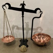 A set of black metal framed weighing scales with copper bowls and five assorted brass weights