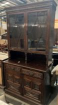 A carved oak wall cabinet with two wood lined glazed door book shelf top section over two drawer