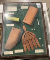 A cased display of river fishing catching aids including eel spears, salmon spears, otter board,