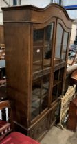 An oak wall cabinet with two upper glazed doors (one missing glass panel) enclosing bookshelves and