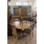 A round pine table on tripod base and six cane dining chairs