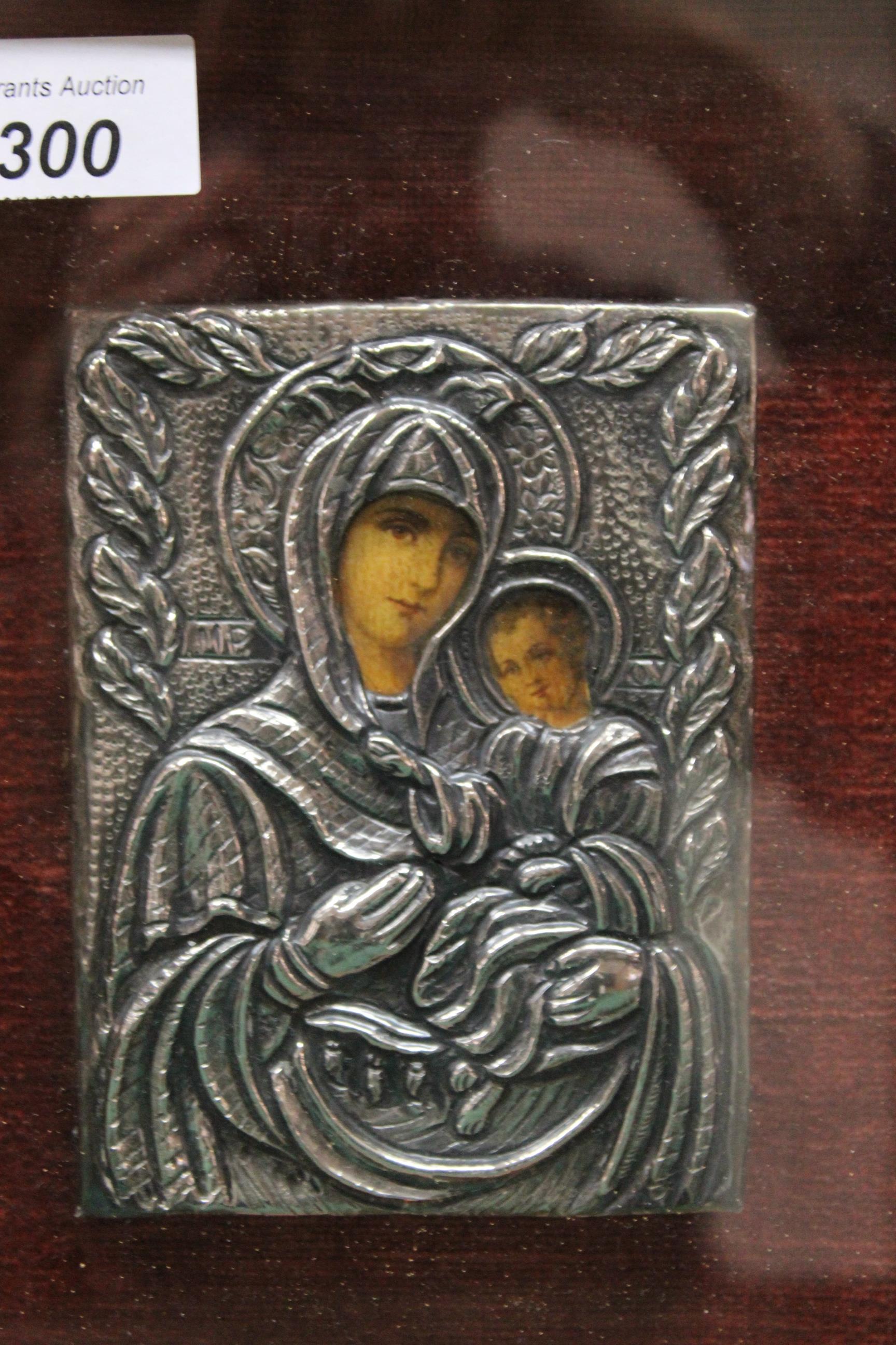 A small white metal covered religious icon housed in a glazed frame depicting the Madonna and Child, - Image 2 of 3