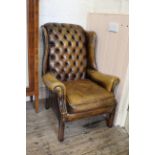 A 20th Century button back brown leather wing armchair