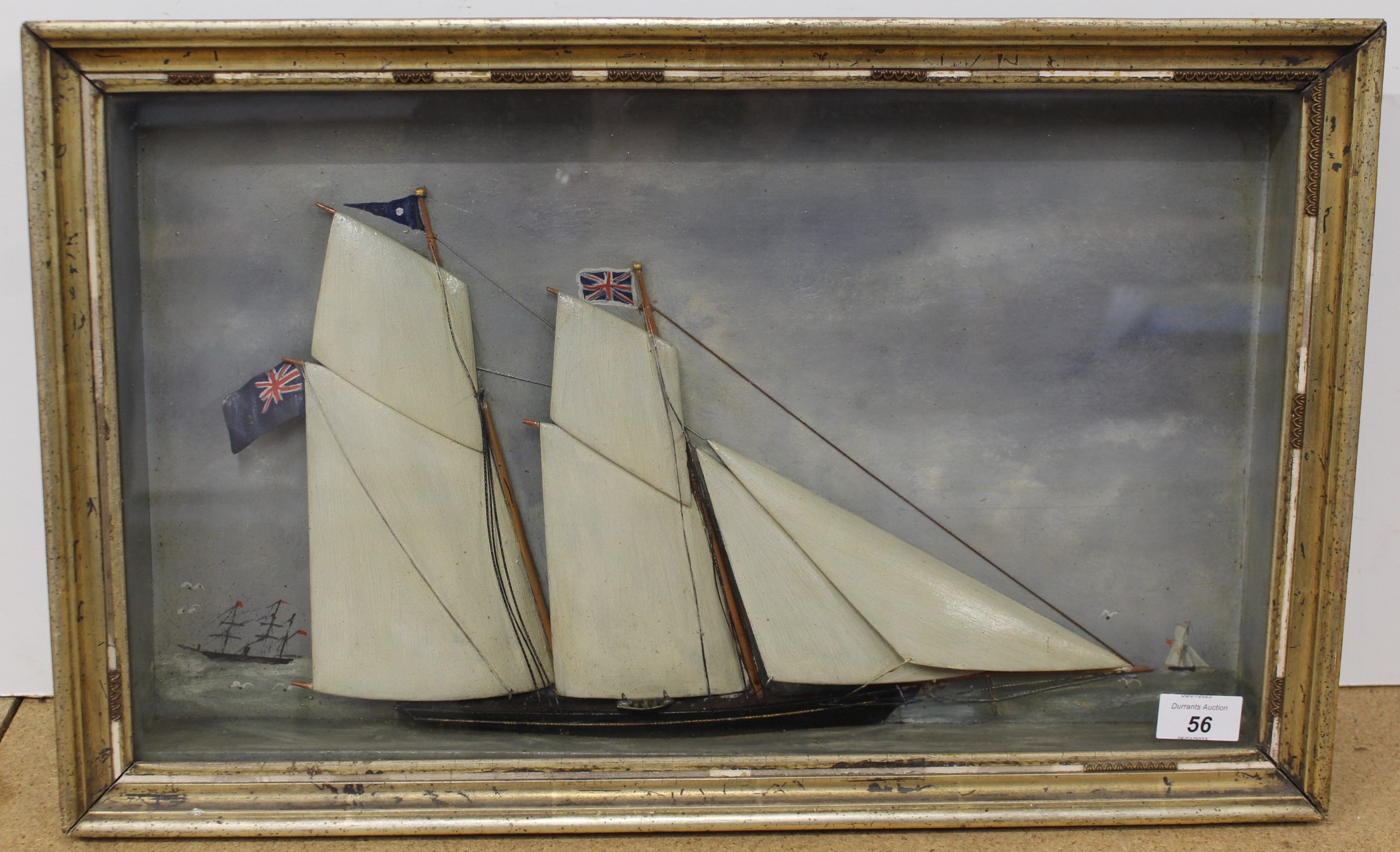 A 19th Century framed and glazed painted wooden half model of a ship in full sail against a painted