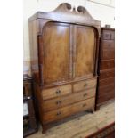 A George IV mahogany four drawer linen press with swan neck pediment and turned columns to doors