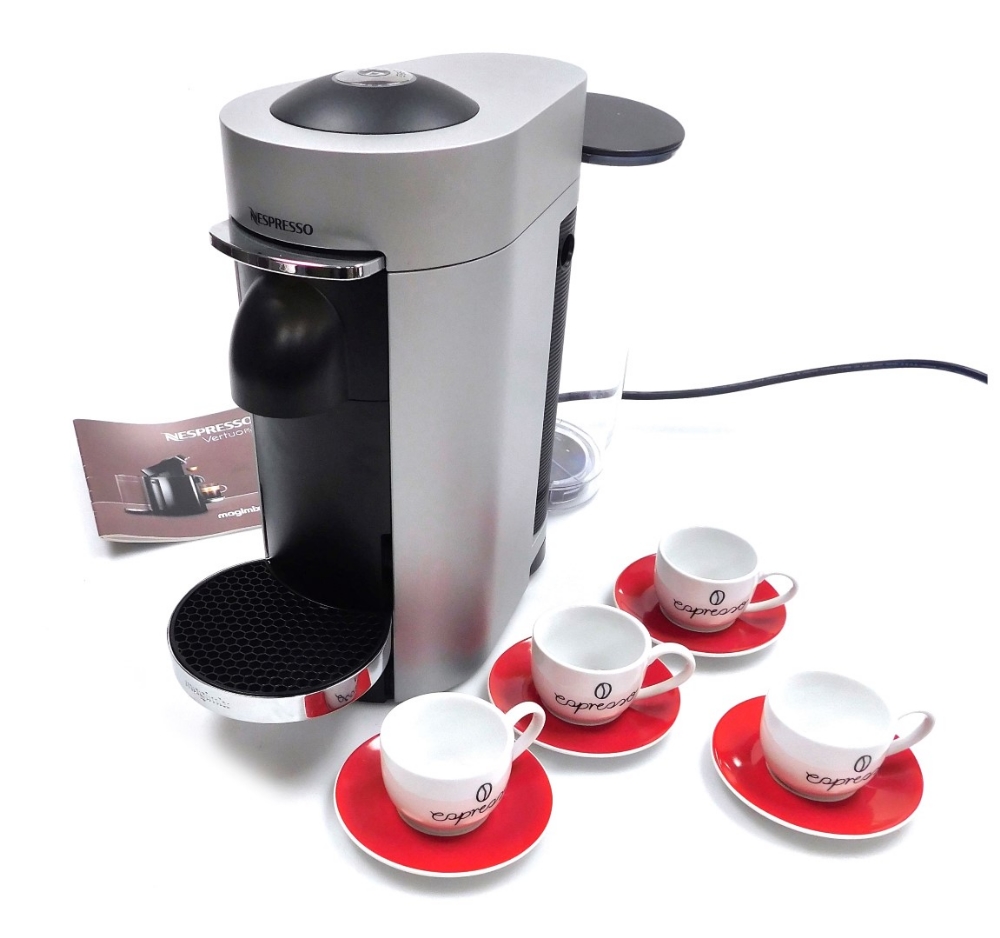 A Nespresso coffee machine, together with four espresso cups and saucers.