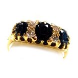 A sapphire three stone ring, set with pairs of diamonds at intervals, in yellow metal stamped 18ct,