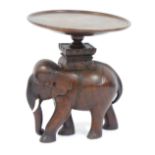 An Indian style mahogany carved elephant table, the elephant base with circular top and plastic tusk