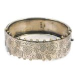 A Victorian silver hinged bangle, the half engraved design of flowers and leaves, with applied ball