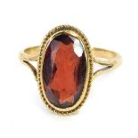 A 9ct gold garnet dress ring, the oval garnet in a rub over setting with rope twist border, on V spl