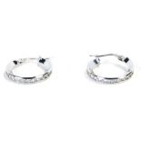 A pair of 9ct white gold diamond hoop earrings, the half hoop design set with tiny diamonds, marked