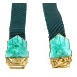 An Art Deco style belt buckle, with two clip clasp set with malachite coloured plastic, on a green r