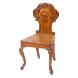 A Victorian oak hall chair, with a foliate carved balloon and shield back, solid seat, raised on cab