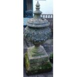 A 19thC reconstituted stone urn shaped finial, decorated with swags of flowers, on a stepped base, 1