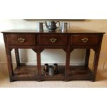 A George II oak dresser base, with single plank top, three frieze drawers with brass swan neck open