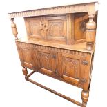 A Gothic style oak court cupboard, the rectangular raised top on supports, with two carved panel doo