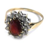 A 9ct gold cluster ring, with central garnet surrounded by cz stones, in a raised basket, ring size