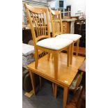 A small draw leaf light oak kitchen table, and four chairs.