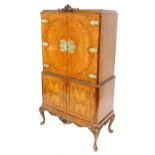 A reproduction walnut drinks cabinet, with carved crest to the top and fitted cabinet below enclosed