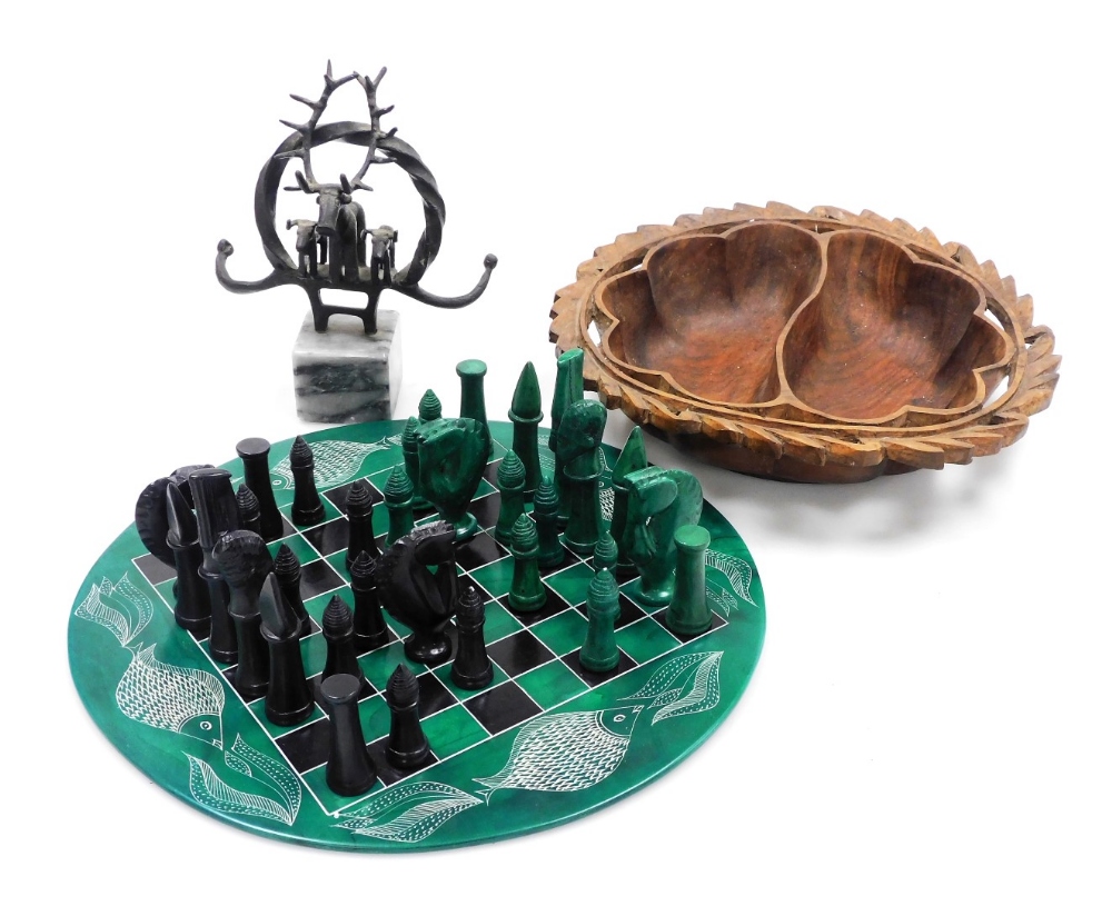 An African hardstone chess set, with black and green pieces, on a circular chess board, decorated to