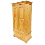 A pine wardrobe, with a moulded cornice above two panelled doors and a drawer, on bracket feet, 103c