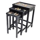 A Chinese black lacquered and hardstone inlaid nest of occasional tables, each glazed top decorated