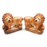 A pair of 19thC Scottish Bowness pottery lions, each modelled standing with a raised paw on a ball,