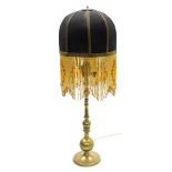 An early 20thC brass table lamp, the shade of black cylindrical form, with gilt trim and beaded hang