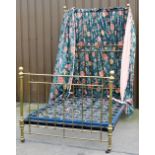 A Victorian brass framed half tester double bed, with floral fabric drapes, bed base and side bars.