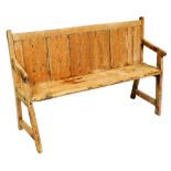 A rustic pine settle or bench, with a tongue and groove back, solid seat, and tapering arms with str