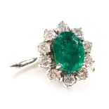 An 18ct white gold emerald and diamond ring, the oval cut emerald in a surround of brilliant cut dia