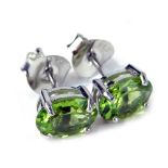 A pair of peridot stud earrings, each with an oval peridot, in a four claw basket setting, on single