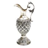 A Continental white metal ewer, the handle moulded with flowers and leaves, the body and foot emboss